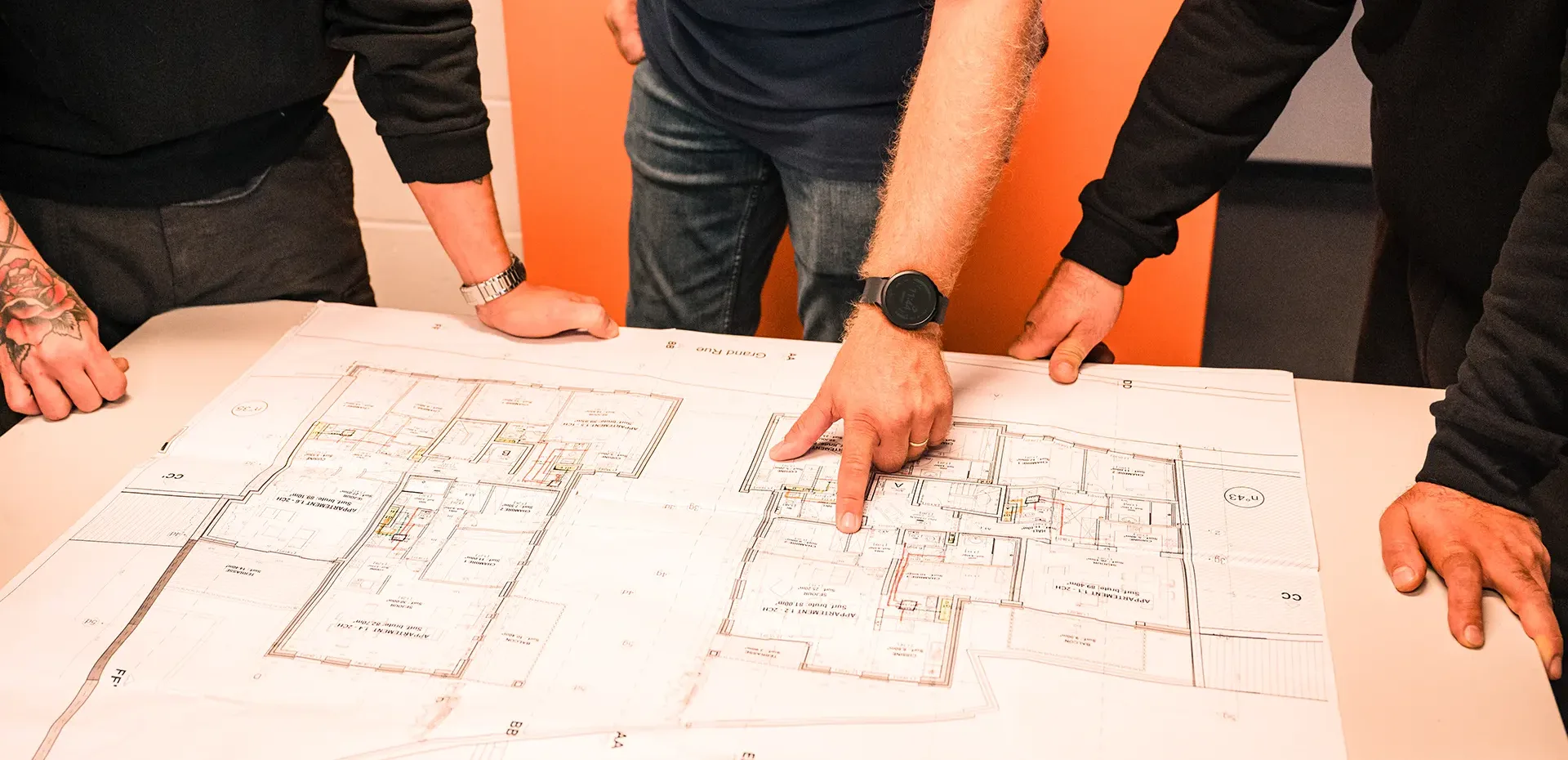 Trois employés de l'entreprise Intérieur et chaleur regardent un plan posé sur une table